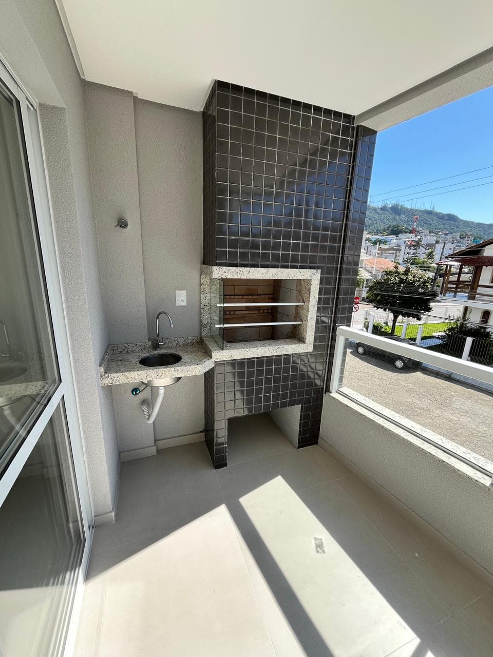Varanda gourmet com churrasqueira e vista aberta do bairro
